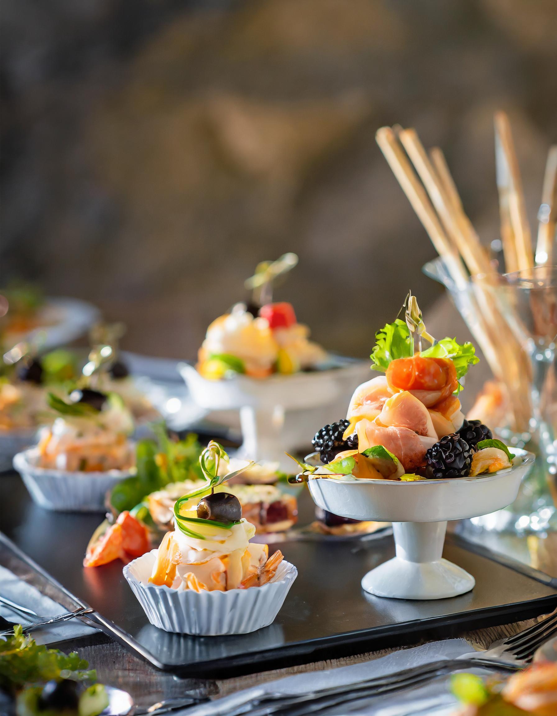 notre service traiteur Petits présentoirs pour apéritif posés sur une planche, avec de la charcuterie et des fruits